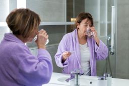 Woman using hormonal therapy in the bathroom at home .