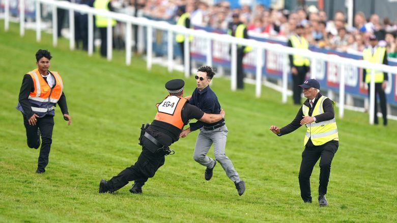 A protestor is tackled by police and stewards during the Betfred Derby during the Derby Festival at Epsom Downs Racecourse, Epsom. Picture date: Saturday June 3, 2023. 