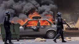 Riot police officers walk near a car set on fire during clashes between supporters of Senegalese opposition leader Ousmane Sonko and security forces after Sonko was sentenced to prison in Dakar Senegal June 1, 2023.