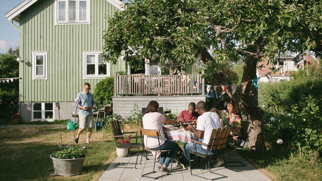 Multi-generation family having lunch at patio during garden party