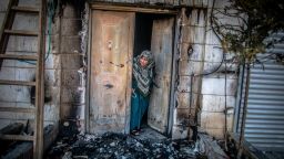 A Palestinian woman looks outside her door that was torched by Jewish settlers in the occupied West Bank town of Huwara.