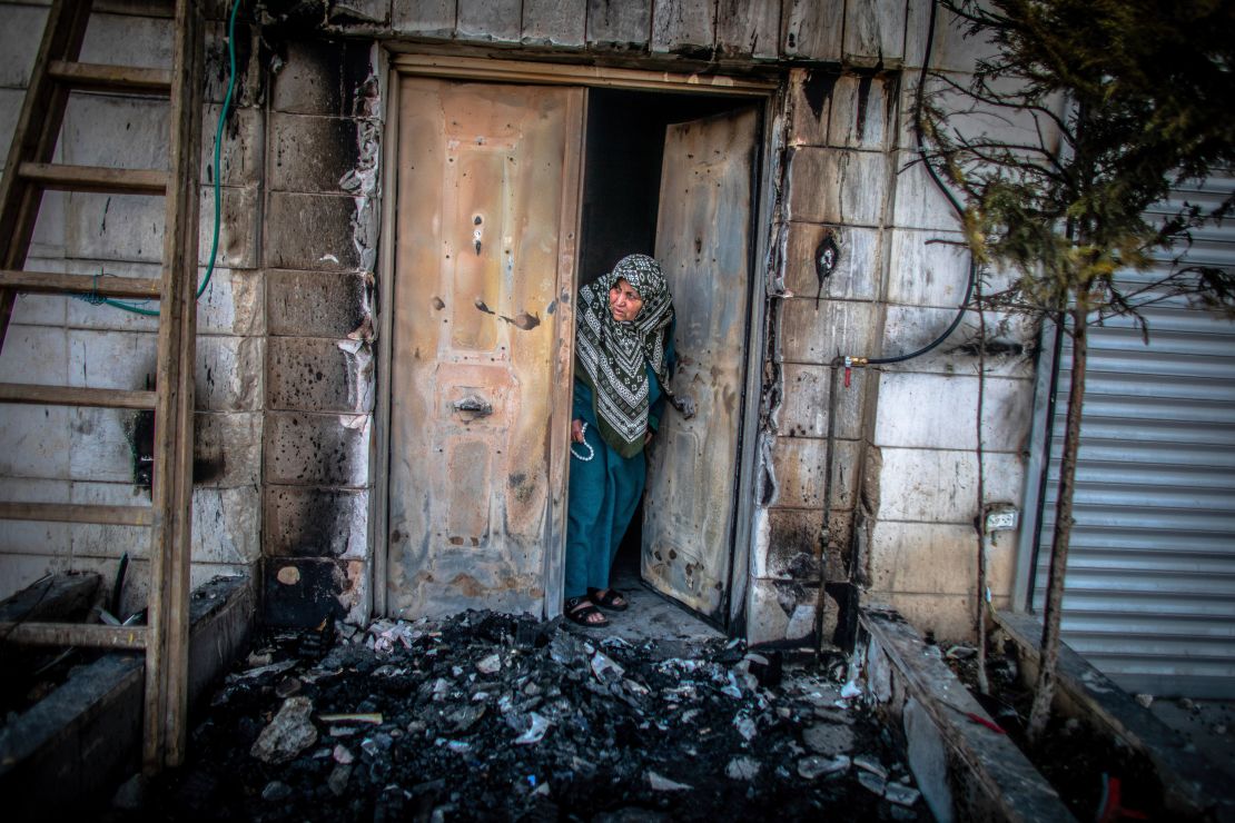 Nawal Dumeidi, 75, peers outside her front door that was torched by settlers in Huwara on February 26.