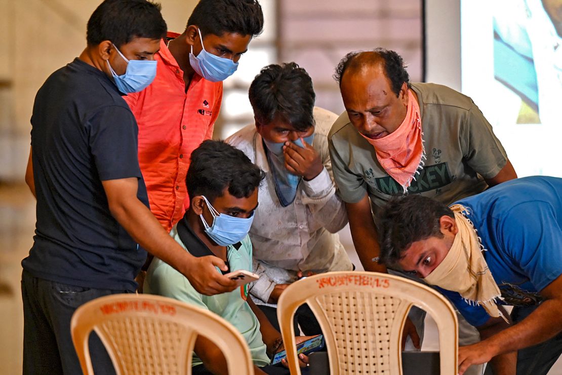 Family members look at photographs on a computer to identify bodies at a temporary mortuary following a train collision near Balasore, in India's eastern state of Odisha, on June 4, 2023. 