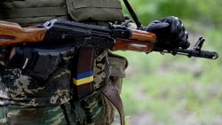 A fighters of the territorial defence unit, a support force to the regular Ukrainian army, holds a Kalshnikov gun decorared with Ukrainian flag ribbon during an exercise as part of the regular combat tactics classes, not far from the Ukrainian town of Bucha, Kyiv region on June 17, 2022. (Photo by Sergei SUPINSKY / AFP) (Photo by SERGEI SUPINSKY/AFP via Getty Images)