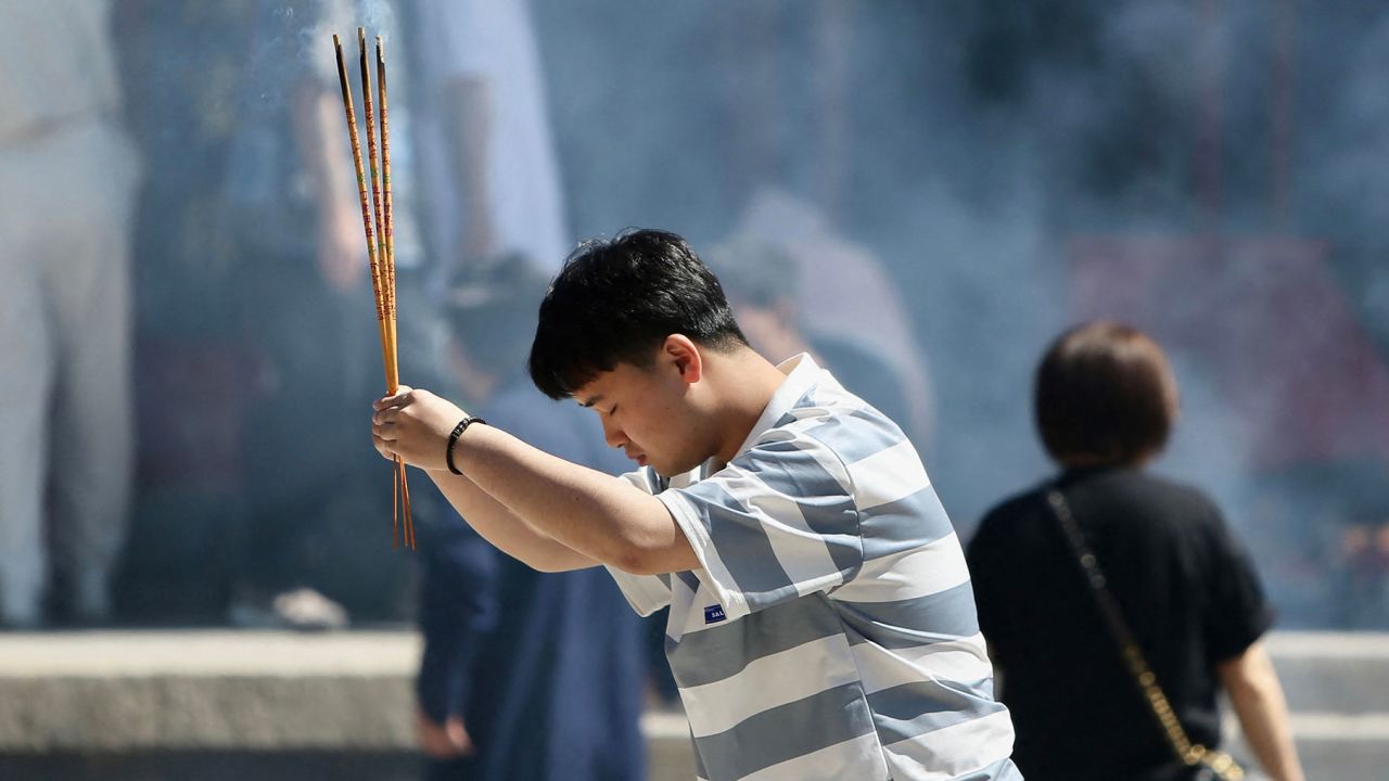 A student holds burning incense sticks as he prays for good results ahead of the gaokao at a temple in Shenyang, China.