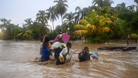 Residents cross the submerged Route Nationale 2 at L'Acul in the Arrondissement of Léogâne,  37 km west of Port-au-Prince, Haiti, on June 3, 2023, during heavy rains.