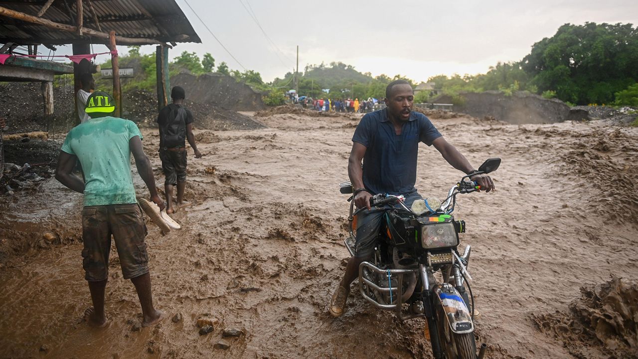 Resident wade through flooded roads in neighborhoods of Petit-Goâve, Haiti.