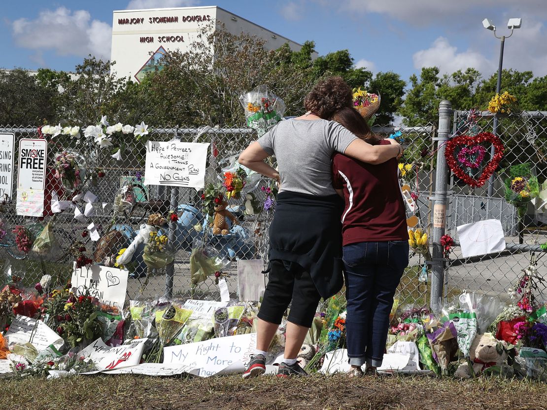 PARKLAND, FL - FEBRUARY 23:  Margarita Lasalle (R), the budget keeper, and Joellen Berman, Guidance Data Specialist, look on at the memorial in front of Marjory Stoneman Douglas High School as teachers and staff are allowed to return to the school for the first time since the mass shooting on campus on February 23, 2018 in Parkland, Florida. Police arrested 19-year-old former student Nikolas Cruz for killing 17 people at the high school.
