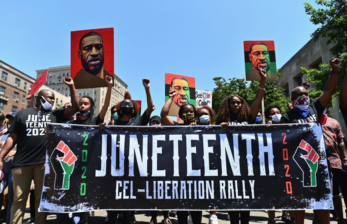 Demonstrators at a 2020 Juneteenth rally in New York hold up pictures of George Floyd. 