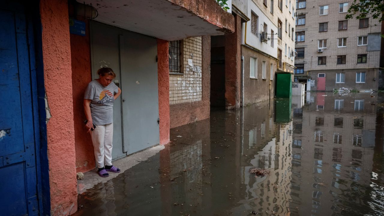 Olena stands next to the entrance to her house on a flooded street, after the Nova Kakhovka dam breached in Kherson, Ukraine, on June 6.