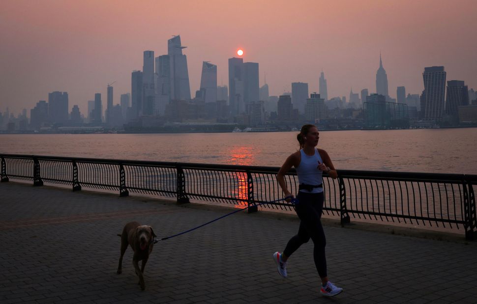 A woman jogs along the Hudson River as a smoky haze hangs over the New York City skyline shortly after sunrise on June 7.