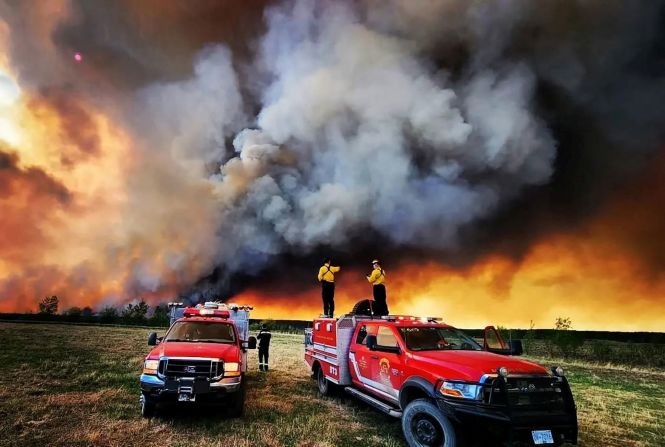 Firefighters stand on a truck while battling a blaze near Fort St. John, British Columbia, on May 14.