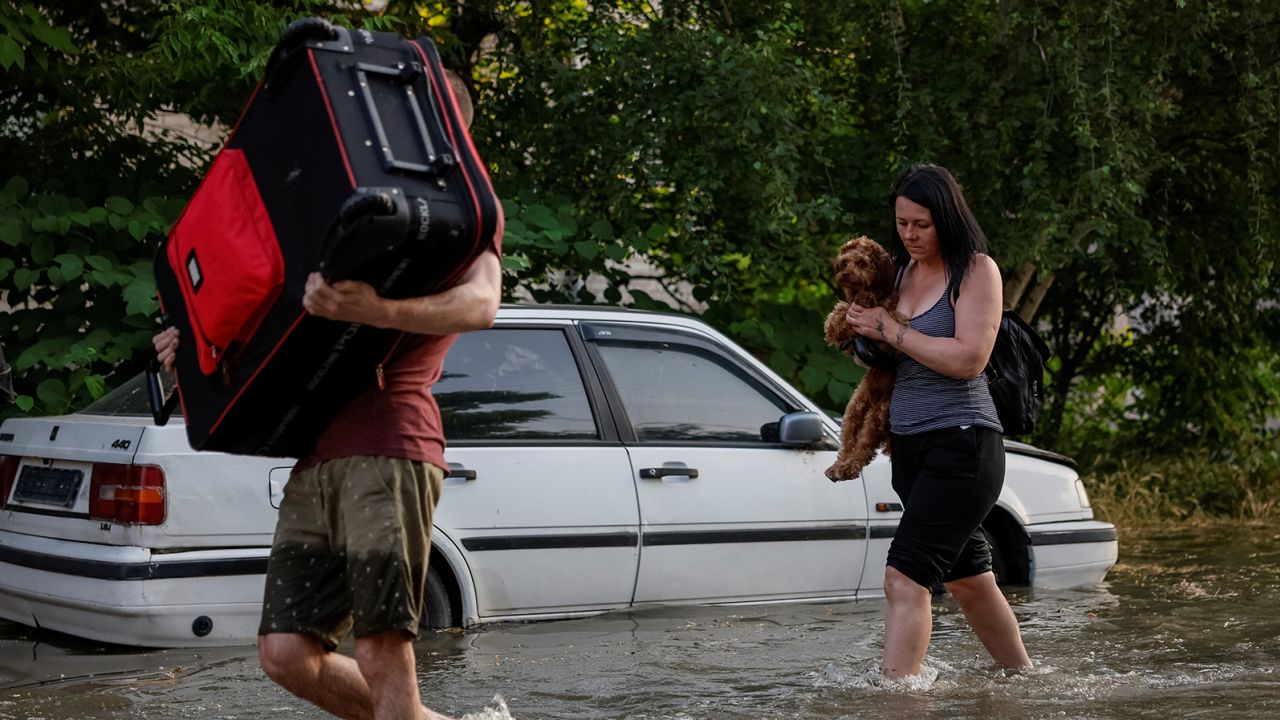 Local residents carry their personal belongings on a flooded street after the Nova Kakhovka dam collapsed, in Kherson, Ukraine, on June 6.