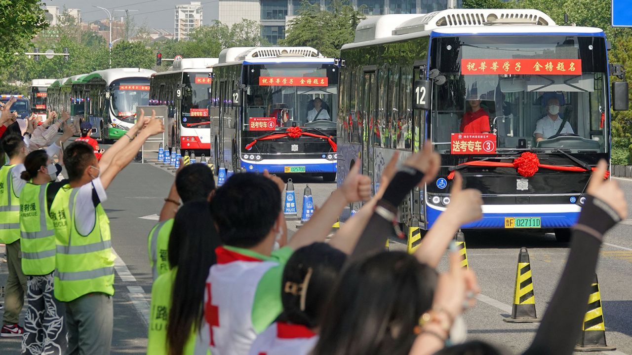 People make thumbs-up gestures to buses carrying students to the gaokao entrance exam in Yantai, China, on June 7.