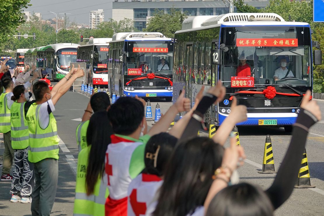 People make thumbs-up gestures to buses carrying students to the gaokao entrance exam in Yantai, China, on June 7.