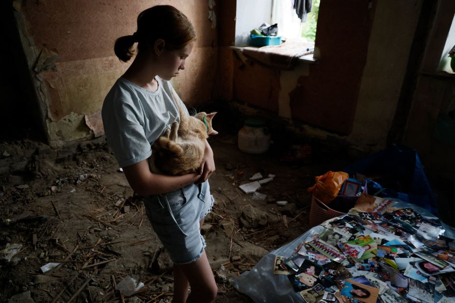 Angelina Kopayeva, 12, looks at family photographs that were laid out to dry in her home in Kherson on June 7.