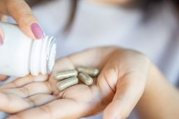 closeup woman hand taking herb medicine tablets