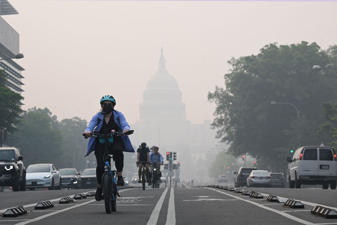 A cyclist rides under a blanket of haze partially obscuring the US Capitol in Washington, DC, on June 8, 2023. Smoke from Canadian wildfires have shrouded the US East Coast in a record-breaking smog, forcing cities to issue air pollution warnings and thousands of Canadians to evacuate their homes. The devastating fires have displaced more than 20,000 people and scorched about 3.8 million hectares (9,390,005 acres) of land. Prime Minister Justin Trudeau described this wildfire season as the country's worst ever. (Photo by Mandel NGAN / AFP) (Photo by MANDEL NGAN/AFP via Getty Images)
