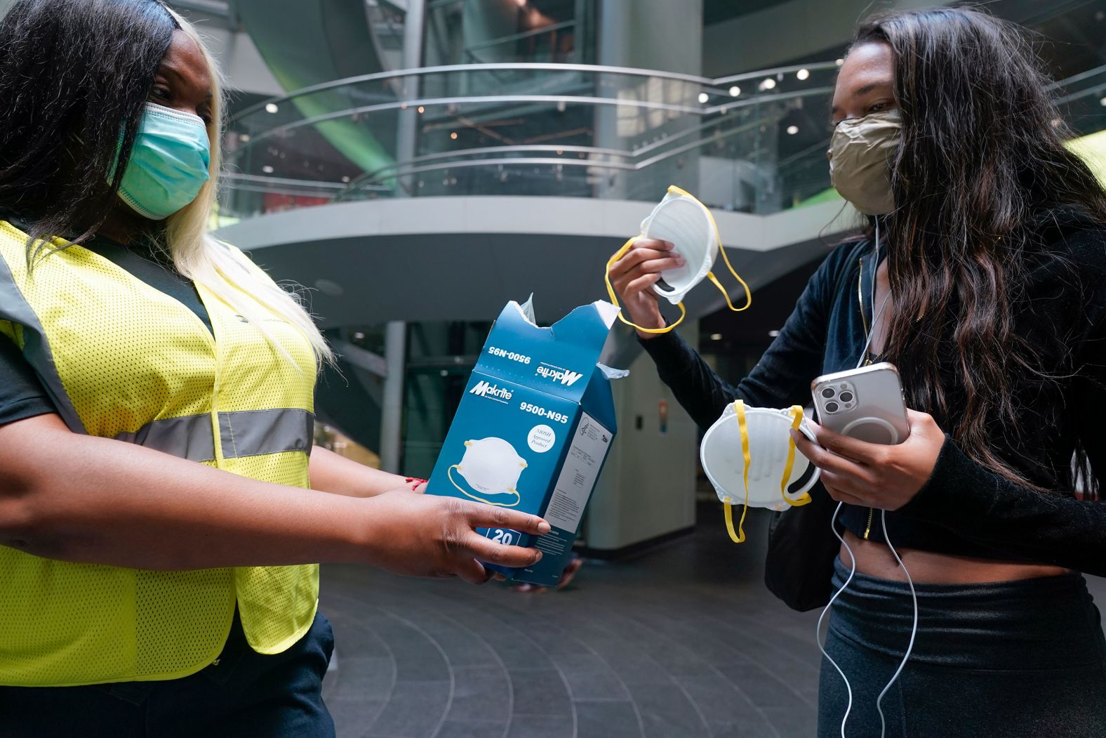 Transit employee Shanita Hancle, left, hands out masks to commuters at a subway station in New York on June 8.