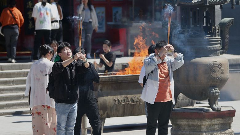 People hold burning incense sticks as they pray for good results ahead of the National College Entrance Examination (NCEE), known as "gaokao", at a temple in Shenyang, in China's northeastern Liaoning province on June 5, 2023.