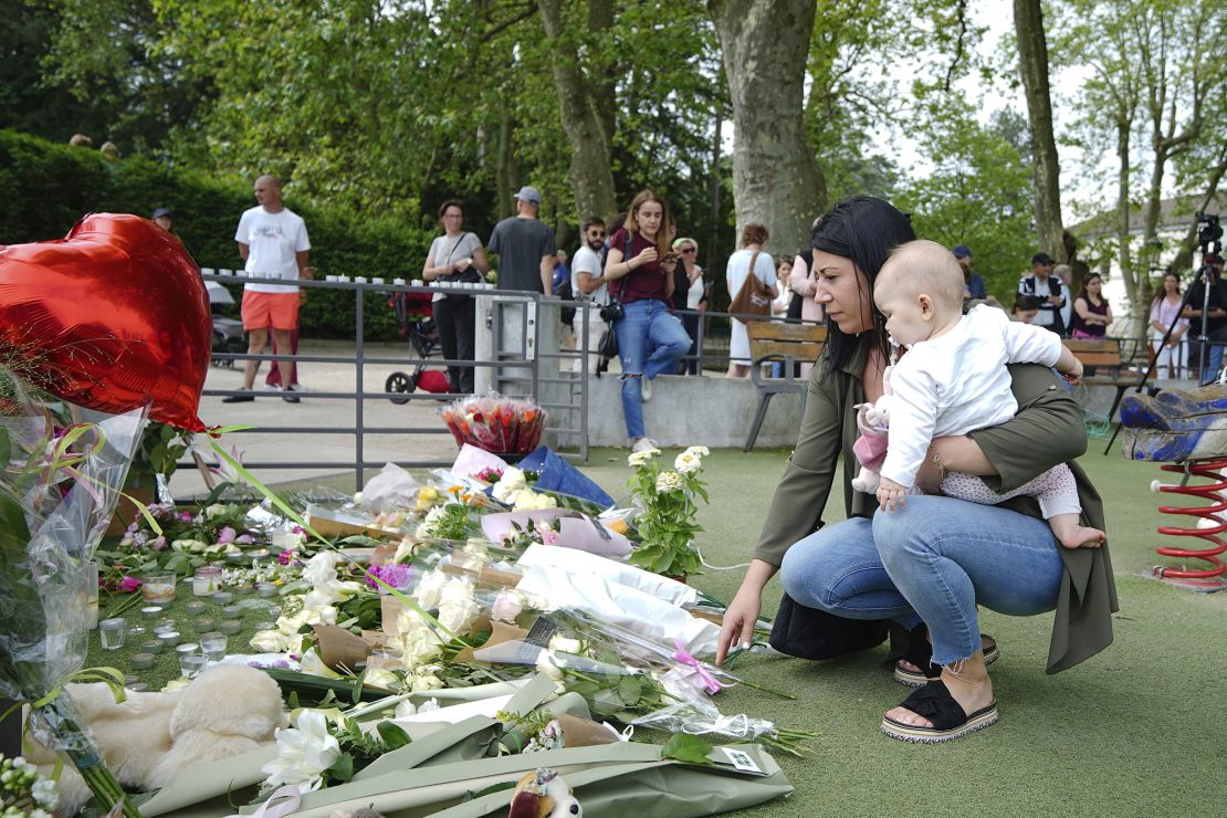 People lay flowers near the scene at a lakeside park in Annecy, France, on Friday, after a knife attack left four children and two adults wounded.