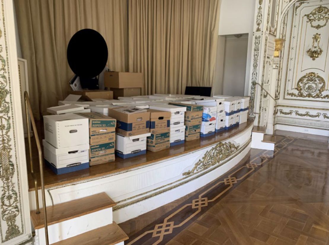 Boxes of classified documents are stored inside the Mar-a-Lago Club's White and Gold Ballroom in this photo included in Donald Trump's federal indictment.