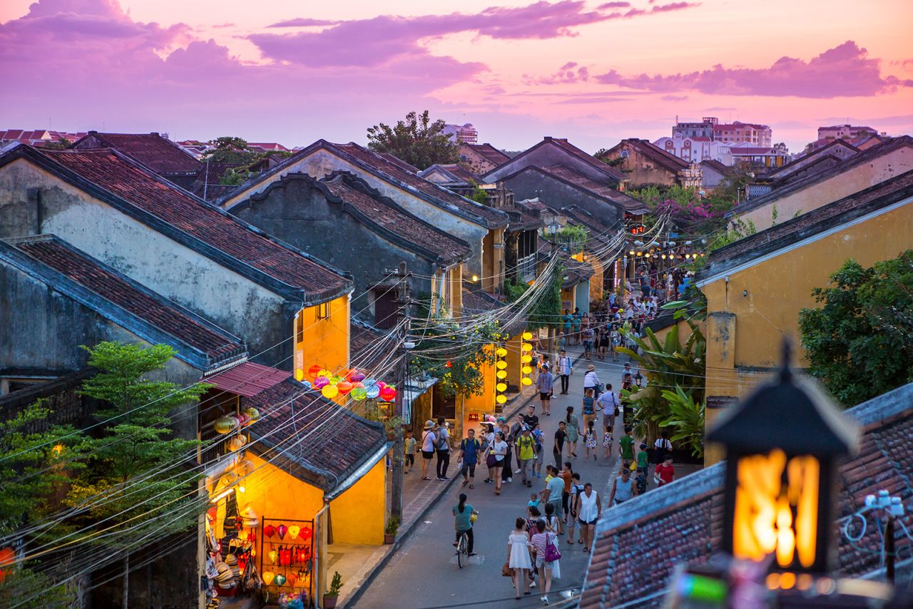 Tourists walk down the colonial streets in historic old town Hoi An. Chinese lanterns illuminate the walkways.