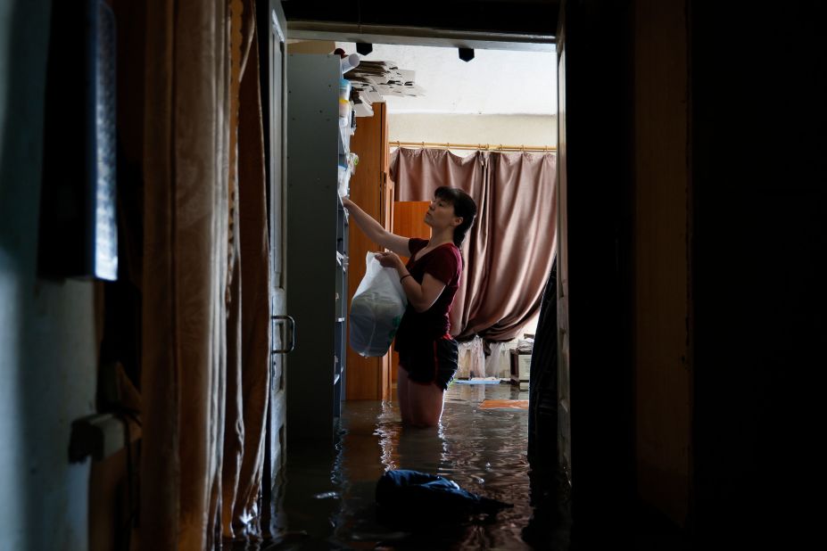A woman helps a family rescue their belongings from flooding in Kherson on Wednesday, June 7.