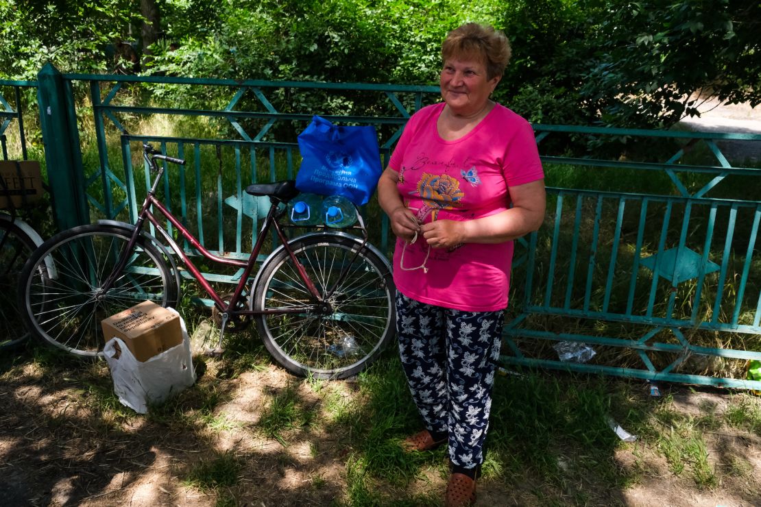 Olga Shumska, 72, has collected her box of aid and prepares to head home on a bicycle, despite the constant shelling.