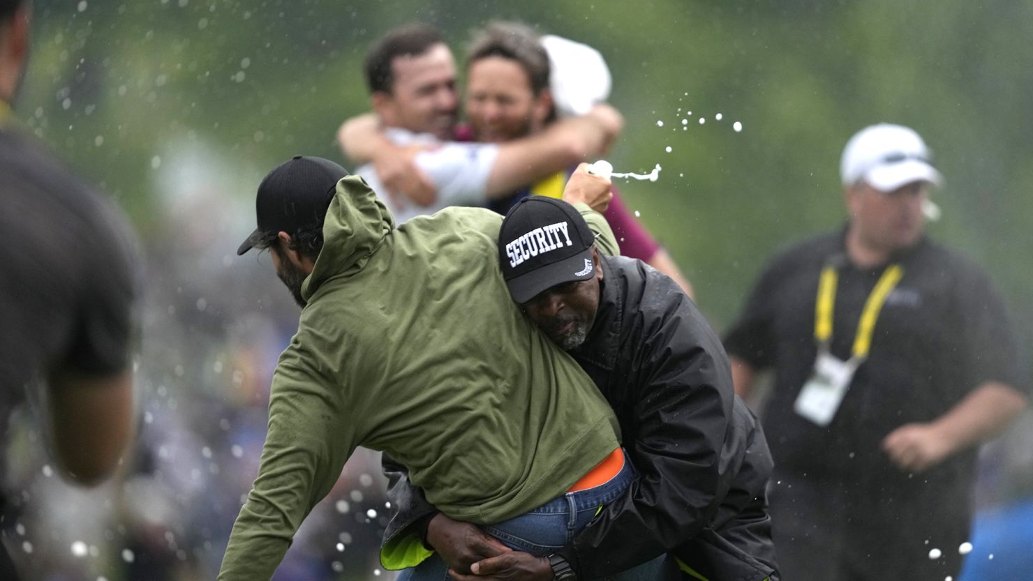 Canadian golfer Adam Hadwin, left, is tackled by a security guard when he tries to celebrate with compatriot Nick Taylor, background left, after Taylor won the Canadian Open in Toronto on Sunday.