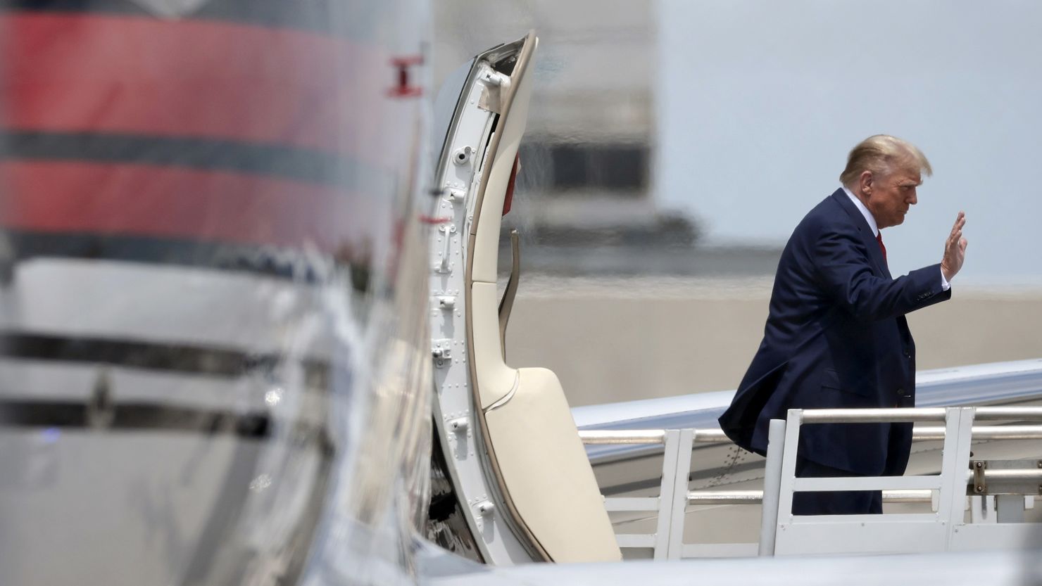Former President Donald Trump waves as he arrives at the Miami airport on June 12, 2023.