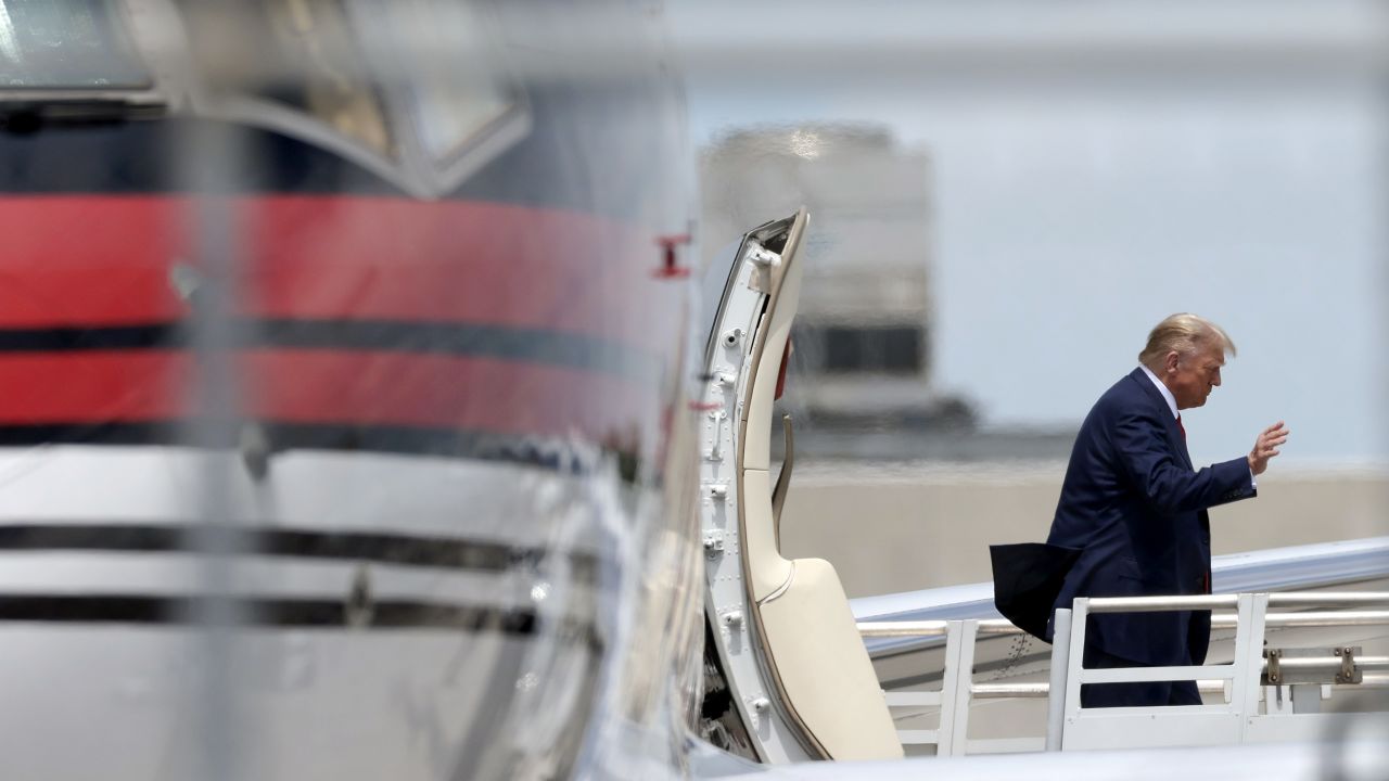 Former President Donald Trump waves as he arrives at the Miami International Airport on June 12, 2023 in Miami.