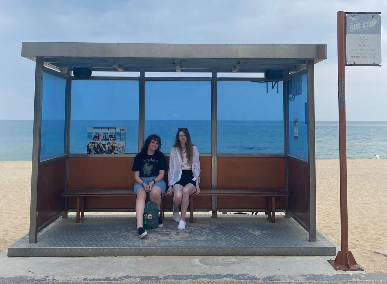 Los fanáticos de BTS Katie Myles (L) y Rowan Joss (R) en la parada de autobús de BTS en el este de Corea del Sur, donde la banda llevó la portada del álbum a 