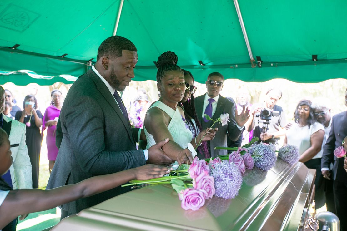 Pamela Dias, the mother of Ajike Owens, center, puts roses on the casket at the grave after the funeral for Owens on June 12, 2023.