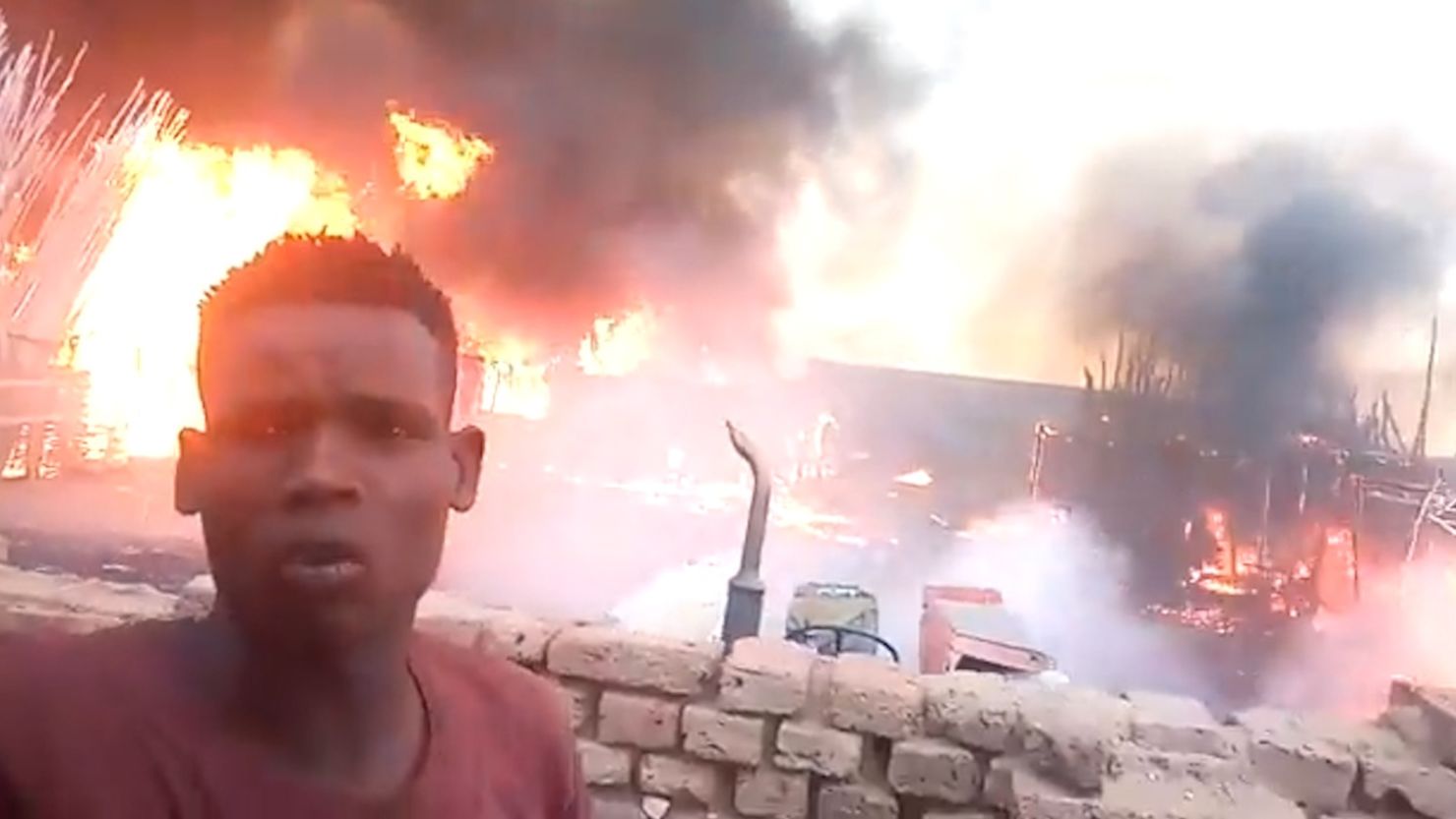 A man stands in front of the Abu Showk market as it goes up in the flames. The market services a camp for internally displaced people in Darfur's al-Fashir. 
