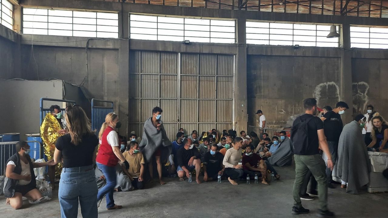 Survivors sit in a warehouse at the port in Kalamata town.