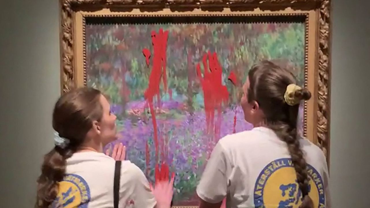 This handout video grab taken from footage provided by Aterstall Vatmarker on June 14 shows two activists smearing paint on the painting "The Artist's Garden at Giverny" by French artist Claude Monet at the National Museum in Stockholm, Sweden.
