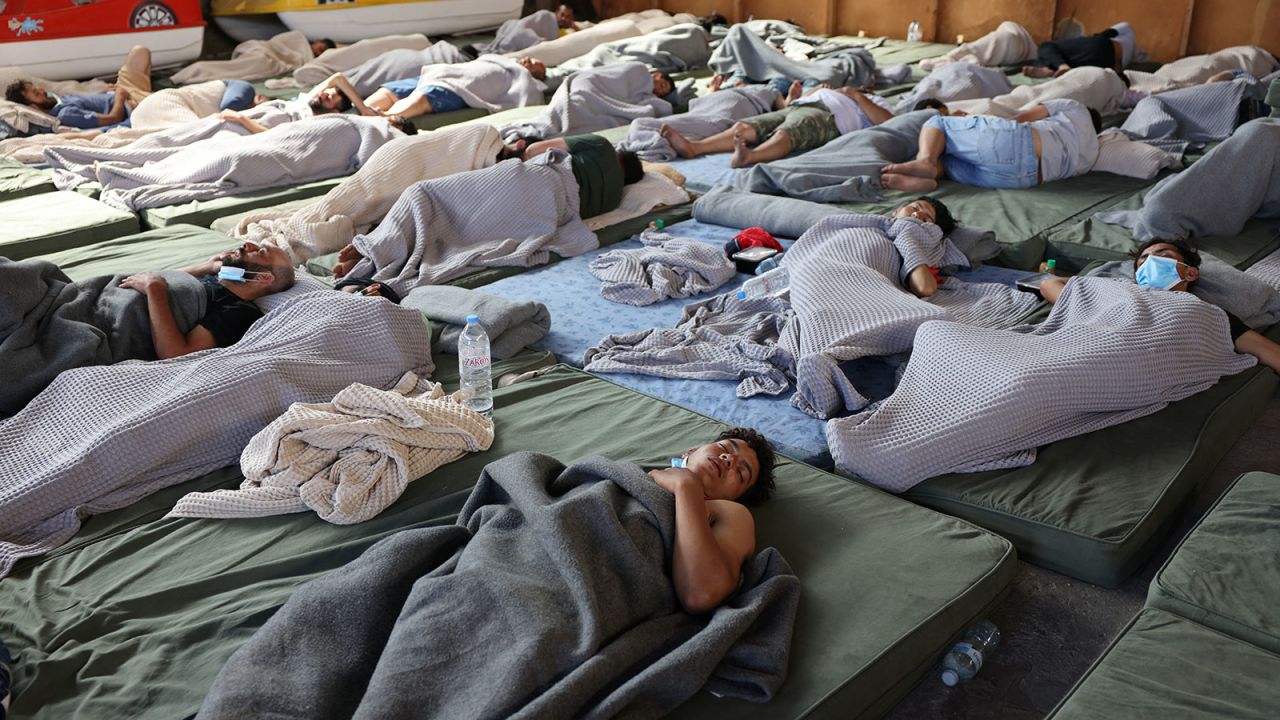 People rest in a shelter, following a rescue operation, after their boat capsized at open sea.