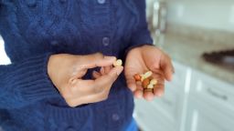 Midsection of woman snacking on handful of mixed nuts