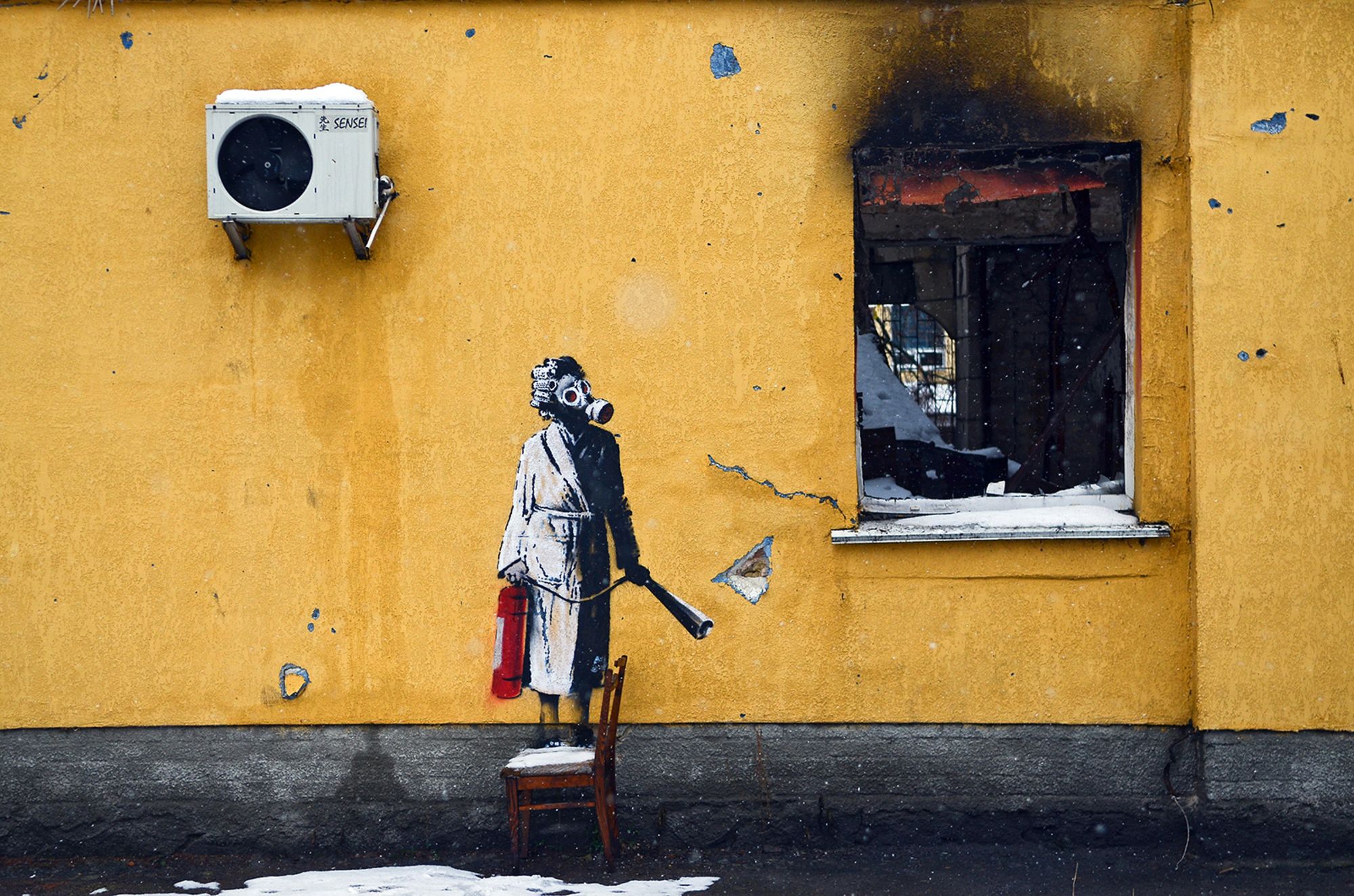 HOSTOMEL, UKRAINE - NOVEMBER 26, 2022 - The mural by England-based street artist Banksy depicts a woman in a gas mask standing on a chair and holding a fire extinguisher, Hostomel, Kyiv Region, northern Ukraine. (Photo credit should read Oleksandra Butova / Ukrinform/Future Publishing via Getty Images)