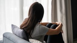 Stressed young Asian woman suffering on depression. Lady sitting alone on sofa in living room at home. Sad, unhappy, disappointed concept. Close up, Copy space
