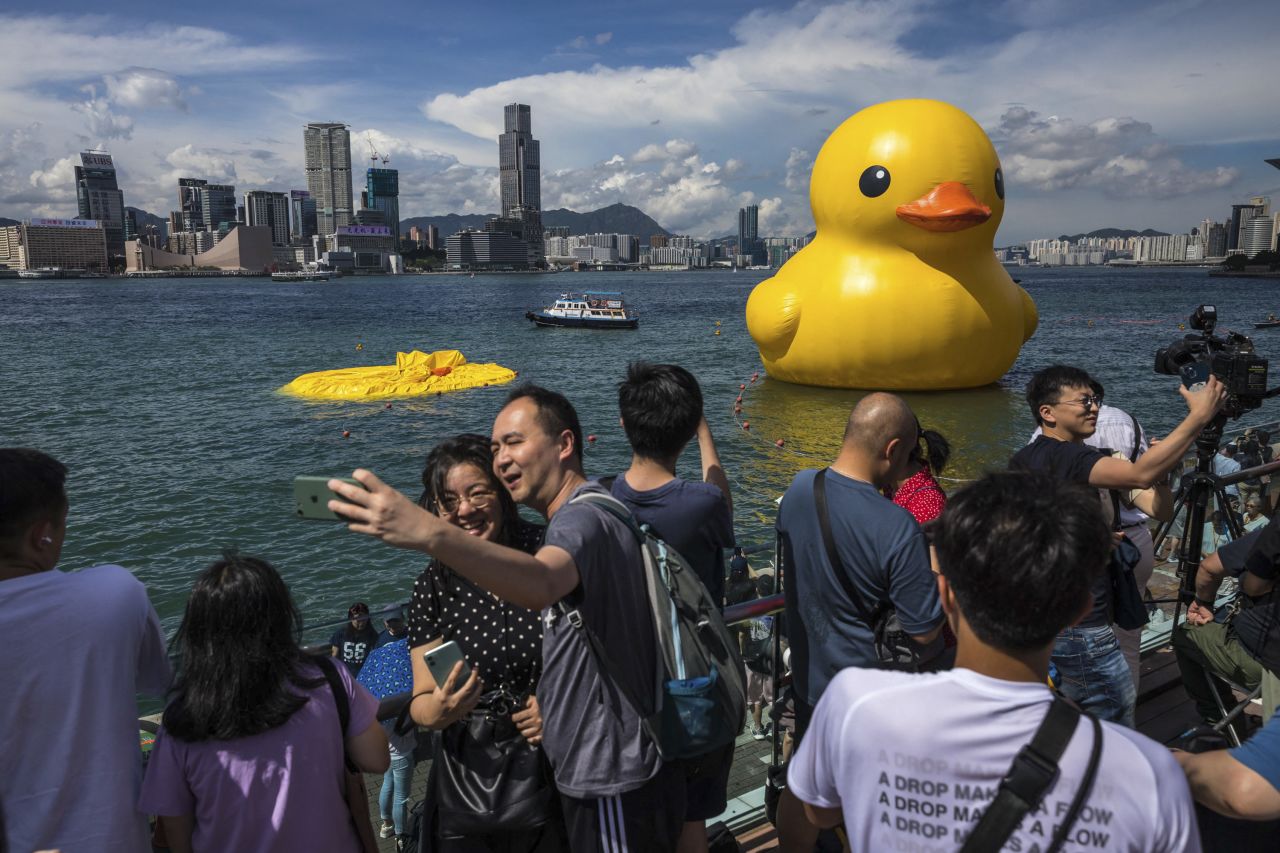 People take a photo Saturday, June 10, as they visit "Double Ducks," the inflatable yellow ducks installed by artist Florentijn Hofman in Hong Kong's Victoria Harbor. One of the giant rubber ducks <a href="https://www.cnn.com/2023/06/10/asia/rubber-duck-deflated-hong-kong-intl/index.html" target="_blank">had been deflated</a> to protect it from sweltering temperatures. An inspection found that its surface had stretched in the hot weather.