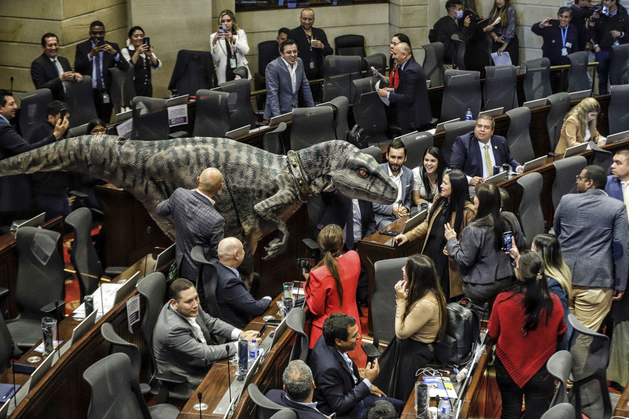 A person wears a dinosaur costume at the Colombia Congress during a debate on climate change on Tuesday, June 13. The demonstrator also held a sign that read "Don't Choose Extinction."