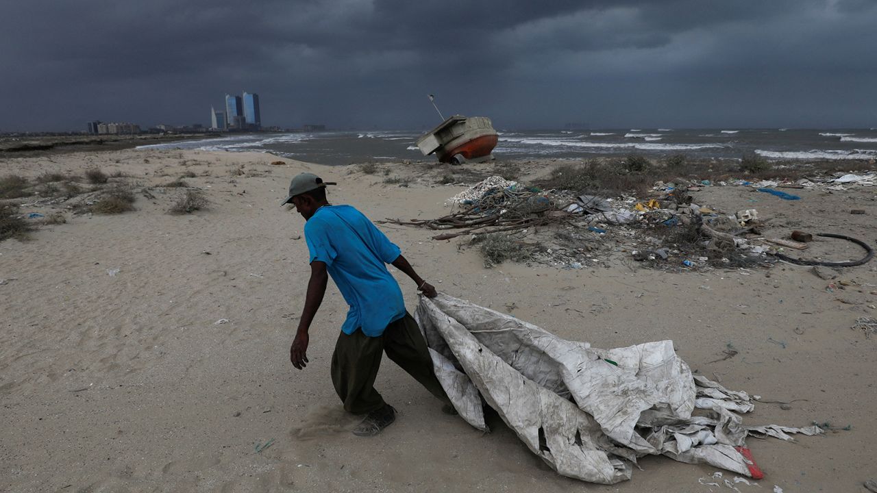 Sooraj, 32, a fisherman and diver, pulls a sheet to cover his belongings, with rain clouds in the background, before the arrival of cyclonic storm, Biparjoy, over the Arabian Sea, in Karachi, Pakistan June 15, 2023.