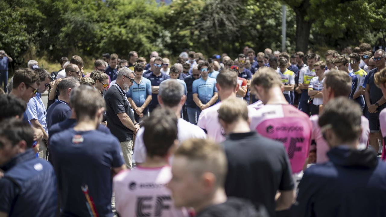Event director Olivier Seine, center left, holds a minute's silence for Gino Maeder of Switzerland of Bahrain Victorious, who died after a crash the day before, at the 86 Tour de Suisse UCI cycling race, in Chur, Switzerland Friday, June 16, 2023 (Gian Ehrenzelle/Keystone via AP)