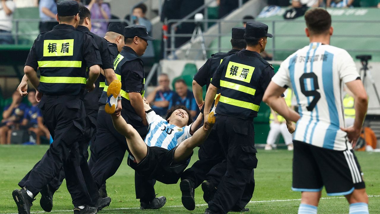 The young pitch invader is carried off the pitch by security officials during a match at the Workers' Stadium in Beijing, China on June 15.