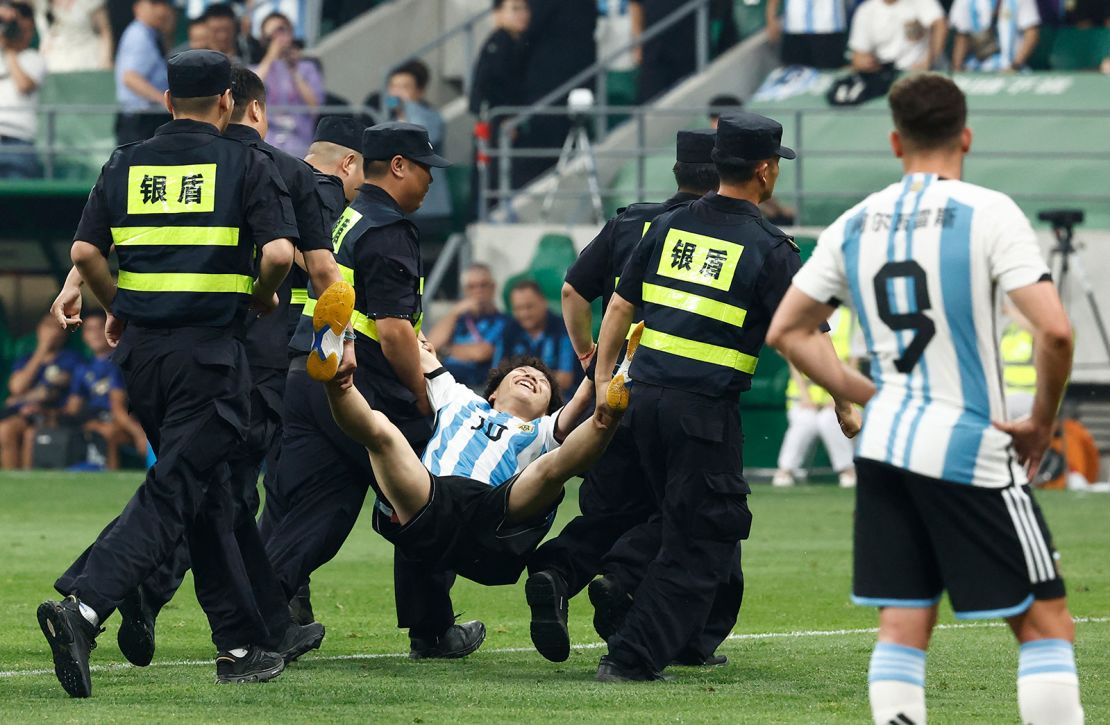 The young pitch invader is carried off the pitch by security officials during a match at the Workers' Stadium in Beijing, China on June 15.