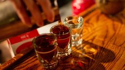 Bartender pouring shots of whiskey into shot glasses