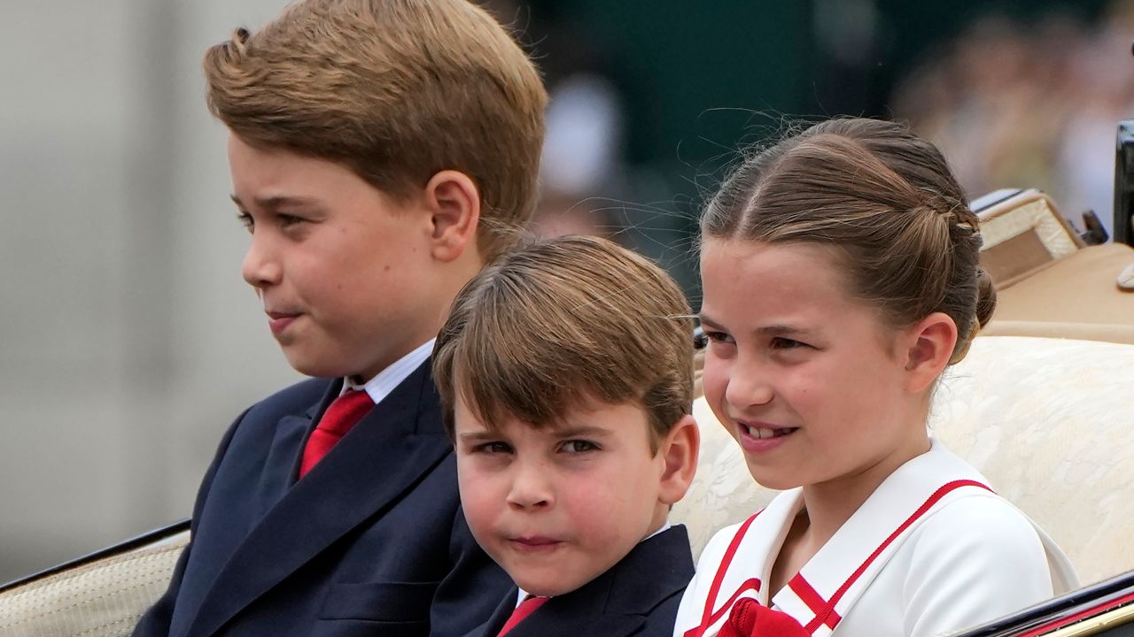 The King's grandchildren, Princes George and Louis and their sister, Princess Charlotte, ride in a horse-drawn carriage to the parade ground.