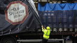  Служител затваря завесата отстрани на камион за доставка, брандиран с логото на ейл "Old Speckled Hen", произведен от Greene King Plc, на камион, натоварен с бирени бурета в пивоварната на компанията в Бъри Сейнт Едмъндс, Великобритания, в сряда , 19 ноември 2014 г. Крис Ратклиф/Блумбърг чрез Getty Images.